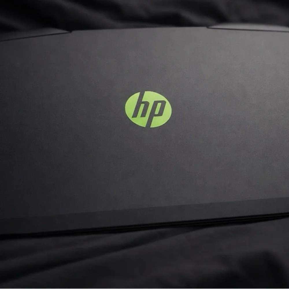 HP Laptop with Green Emblem on Black Surface